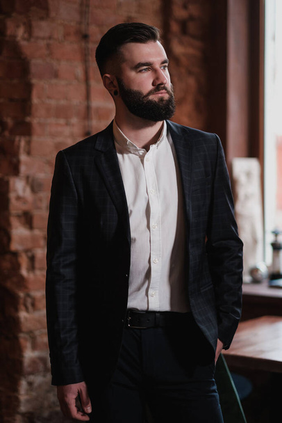 A young handsome man with a beard in a business suit in the interior of a restaurant. - Foto, afbeelding