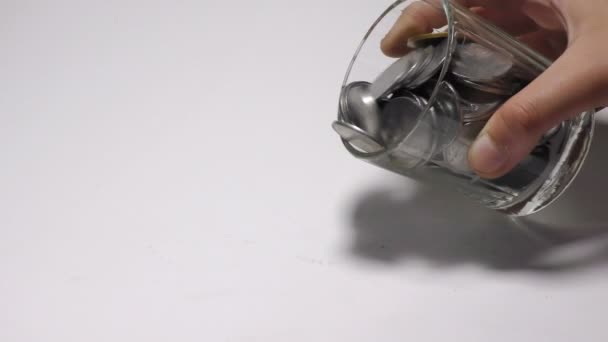 Tirando monedas en la superficie blanca del frasco de vidrio y mostrándolo
. - Metraje, vídeo