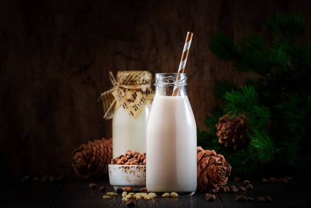 Vegan Cedar nut milk in bottles, closeup, wooden table background. Non dairy alternative milk. Healthy vegetarian food and drink concept. Copy space - Foto, Imagen