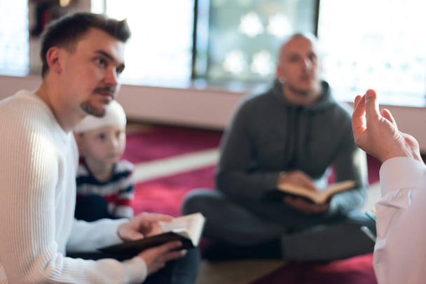 Gruppe verstümmelter religiöser muslimischer Jugendlicher, die gemeinsam in einer schönen modernen Moschee beten und Koran lesen. - Foto, Bild