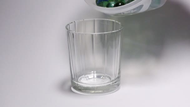 Pouring marble balls in the glass jar and displaying it. - Filmati, video