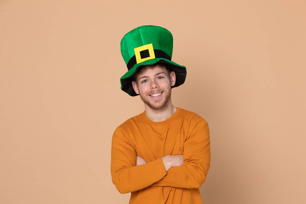 Attractive young guy with a big green hat on a yellow background - Photo, Image