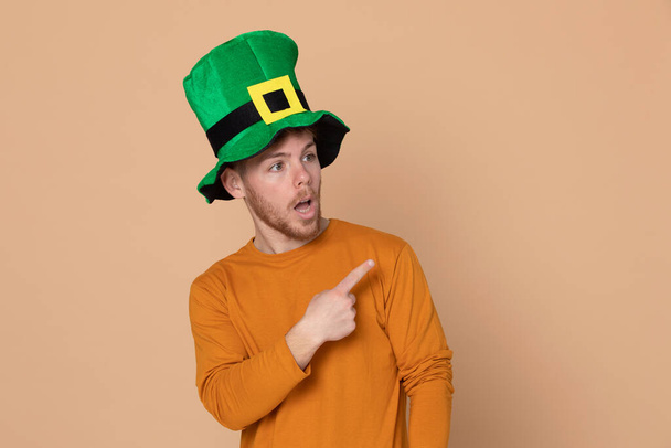 Attractive young guy with a big green hat on a yellow background - Foto, afbeelding