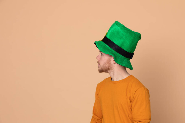 Ελκυστικός νεαρός με μεγάλο πράσινο καπέλο σε κίτρινο φόντο. - Φωτογραφία, εικόνα