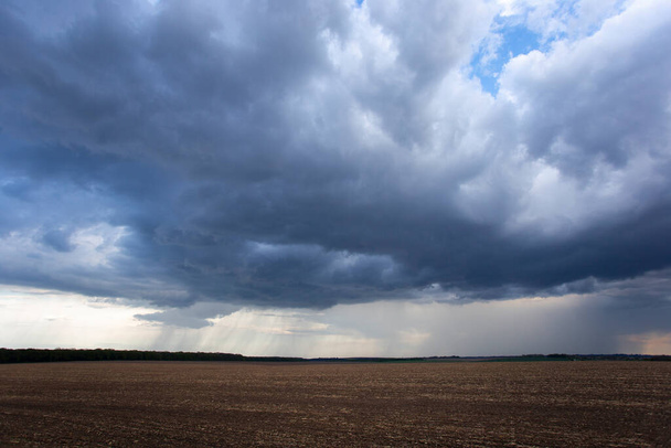 A thundercloud hovered over the field, from which it rained in the distance - Photo, Image