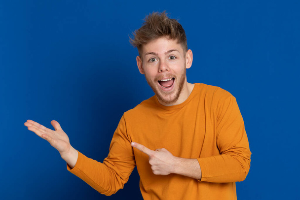 Attractive young guy with a yellow T-shirt on a blue background - Photo, Image