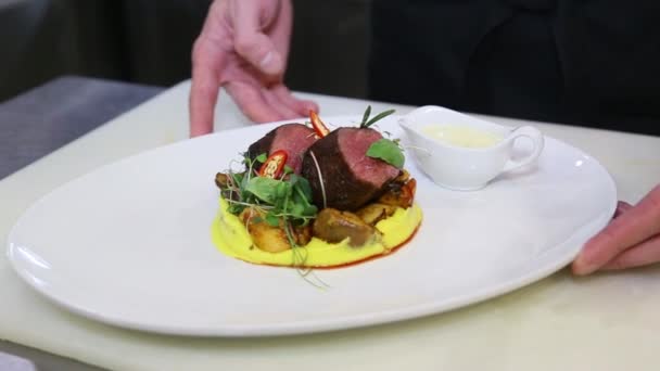 Ο σεφ επιδεικνύει το τελικό πιάτο κρέατος σε ένα πιάτο με σάλτσα - Πλάνα, βίντεο