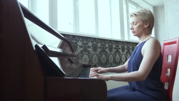 elegant fragile woman plays piano at home in the living room - Materiaali, video