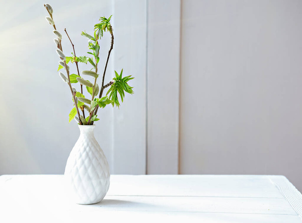 Masanın üzerinde beyaz bir vazoda dallar var. taze ve minimal stil konsepti. Temiz ve dağınık bir oda. İskandinav tasarımı.  - Fotoğraf, Görsel
