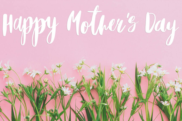 Šťastný Den matek text na kvetoucí jarní květiny kytice na růžovém pozadí. Květinový pozdrav. Šťastné matky den koncept. - Fotografie, Obrázek
