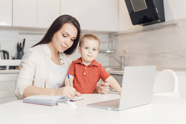 Businesswoman mother woman with small child son working online computer home office - Photo, Image