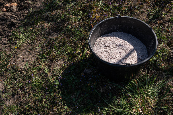 El cubo de plástico negro con un fertilizante granulado
 - Foto, Imagen