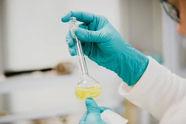 Apparatuur en wetenschap experimenten olie gieten wetenschapper, chemicus met reageerbuis geel maken van onderzoek in het laboratorium - Foto, afbeelding
