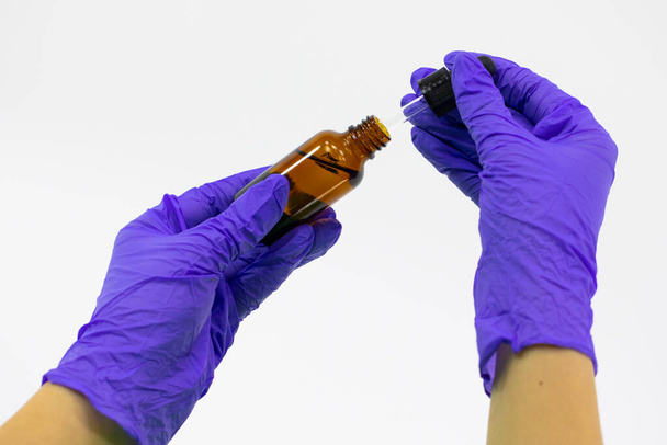 Fermer pot cosmétique en verre avec des composants thérapeutiques dans les mains avec des gants
 - Photo, image