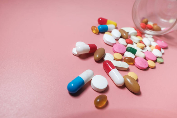 Барвисті таблетки і капсули на рожевому фоні
  - Фото, зображення