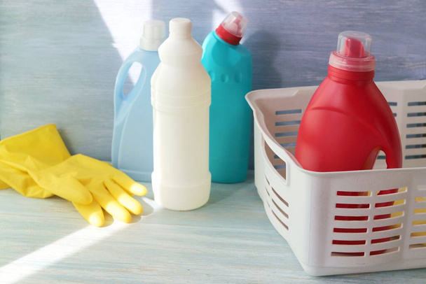  Tekuté prací prostředky v plastových lahvích, gumové rukavice na čištění domu na dřevěném stole, domácí donáška - Fotografie, Obrázek