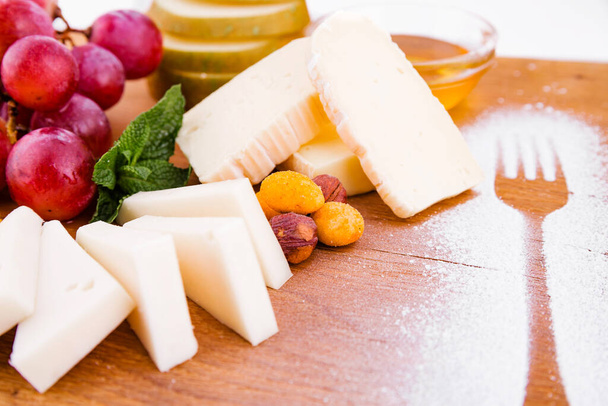 Sýrový talíř na dřevěné desce na bílém pozadí. Vodorovná fotografie - Fotografie, Obrázek