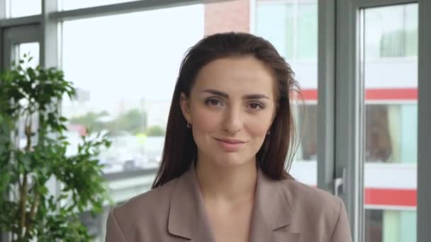 Portrait of attractive young lady entrepreneur smiling looking at camera standing in modern office alone.  - Záběry, video