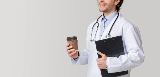 Неузнаваемый врач мужского пола держит медицинскую карту и пьет кофе на вынос
 - Фото, изображение