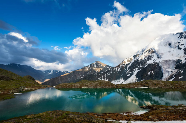 Green lake between mountains in cloudy day - Foto, afbeelding
