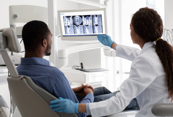 Γυναικείος οδοντίατρος δείχνει στην οθόνη με την εικόνα ακτίνων Χ - Φωτογραφία, εικόνα