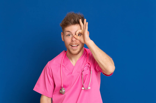 Африканський лікар у рожевій формі на синьому фоні. - Фото, зображення