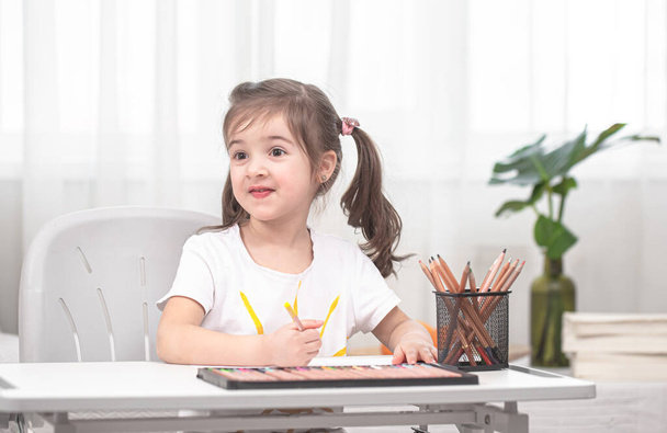 A lány az asztalnál ül és házi feladatot csinál. A gyerek otthon tanul. Otthoni tanulás. A szöveg helye. - Fotó, kép