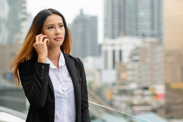 Portrait of young beautiful Asian businesswoman against view of the city - Φωτογραφία, εικόνα