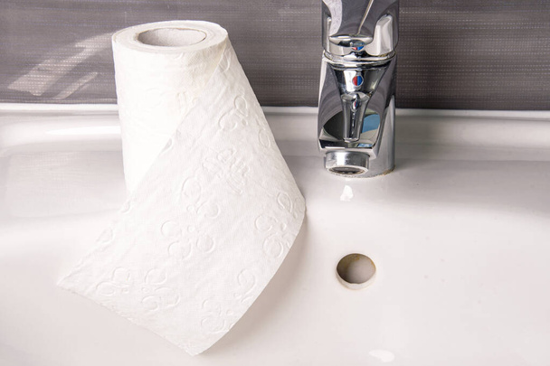 Rollo de papel higiénico en el lavabo con grifo
 - Foto, Imagen