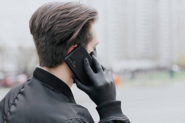 A man is talking on the phone in a protective black glove - Fotoğraf, Görsel