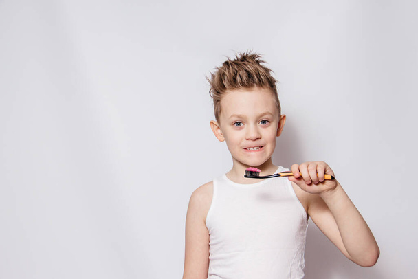 Gelukkige jongen poetst zijn tanden en lacht. Hygiëneprocedures van de mondholte. - Foto, afbeelding