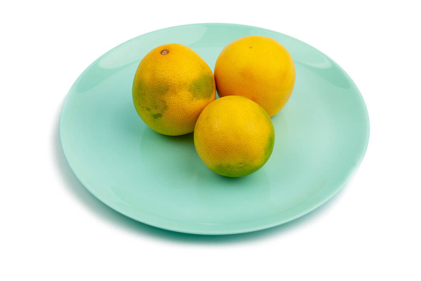 three whole yellow-green grapefruit on a turquoise plate on a white background. Isolate - Foto, Imagem