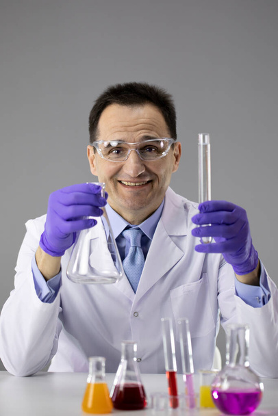 Männlicher Arzt oder Chemiker blaue Handschuhe und Schutzbrille mit Kolben und Schlauch - Foto, Bild