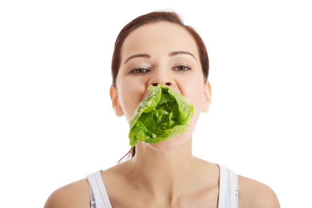 Beautiful woman with leaf of lettuce in mouth. - Fotó, kép