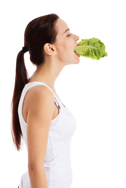 Beautiful woman with leaf of lettuce in mouth. - Fotoğraf, Görsel
