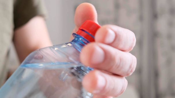 Female hands open a bottle of water in room. Close up. - Foto, afbeelding
