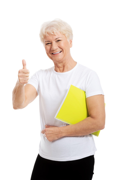 An old woman holding workbook and showing OK. - Zdjęcie, obraz