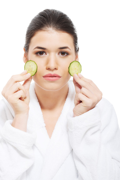 Beautiful woman in bathrobe holding slices of cucumber. - Photo, Image