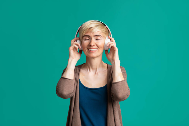 Mosolygó nő vezeték nélküli fejhallgatóval, szabad hely - Fotó, kép