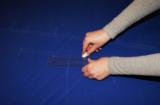 La mano femenina corta la tela con tijeras, cortando la tela
. - Foto, imagen