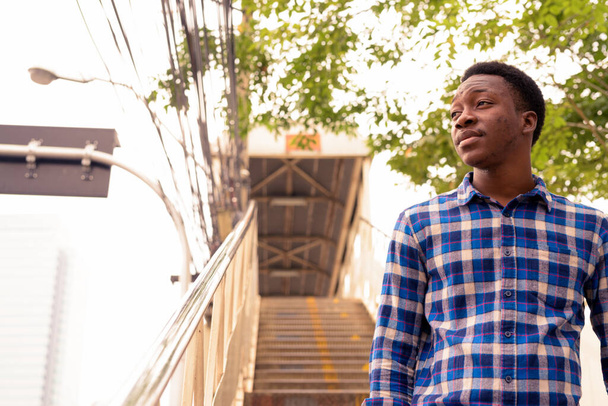 Portrait of young handsome African man at footbridge in the city outdoors - Foto, immagini