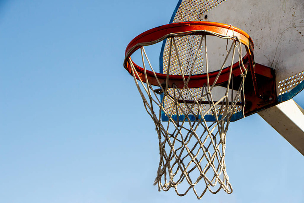 Винтажное баскетбольное кольцо на уличных площадках с голубым небом. Вниз. Селективный фокус
. - Фото, изображение