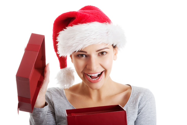 Beautiful woman in santa hat and opening present. - Foto, afbeelding