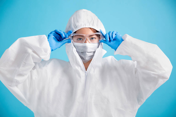 naisten sairaanhoitaja yllään lääketieteellinen naamio turvalasit ja valkoinen suojapuku
. - Valokuva, kuva