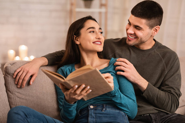 Schönes Paar sitzt zusammen auf Couch und liest Buch - Foto, Bild