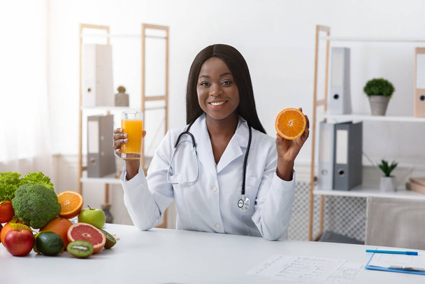 Donna africana dietista raccomandando succo d'arancia fresco
 - Foto, immagini