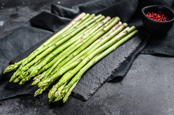 bunch of fresh asparagus on wrought table. Black background. Top view. Copy space. - Photo, Image