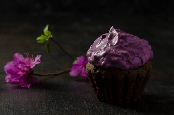 Chocolate cupcakes with beetroot cream on a dark background with flower labrador tea or rhododendron - Photo, Image