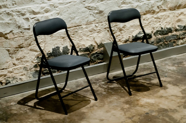 Δύο μοντέρνες μαύρες καρέκλες σε ένα δυνατό ροκ κελί φυλακής - Φωτογραφία, εικόνα