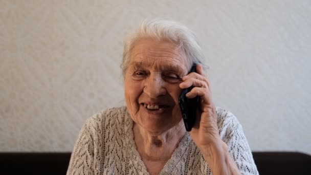 Onnellinen vanha nainen puhuu puhelimessa ja hymyilee.
. - Materiaali, video